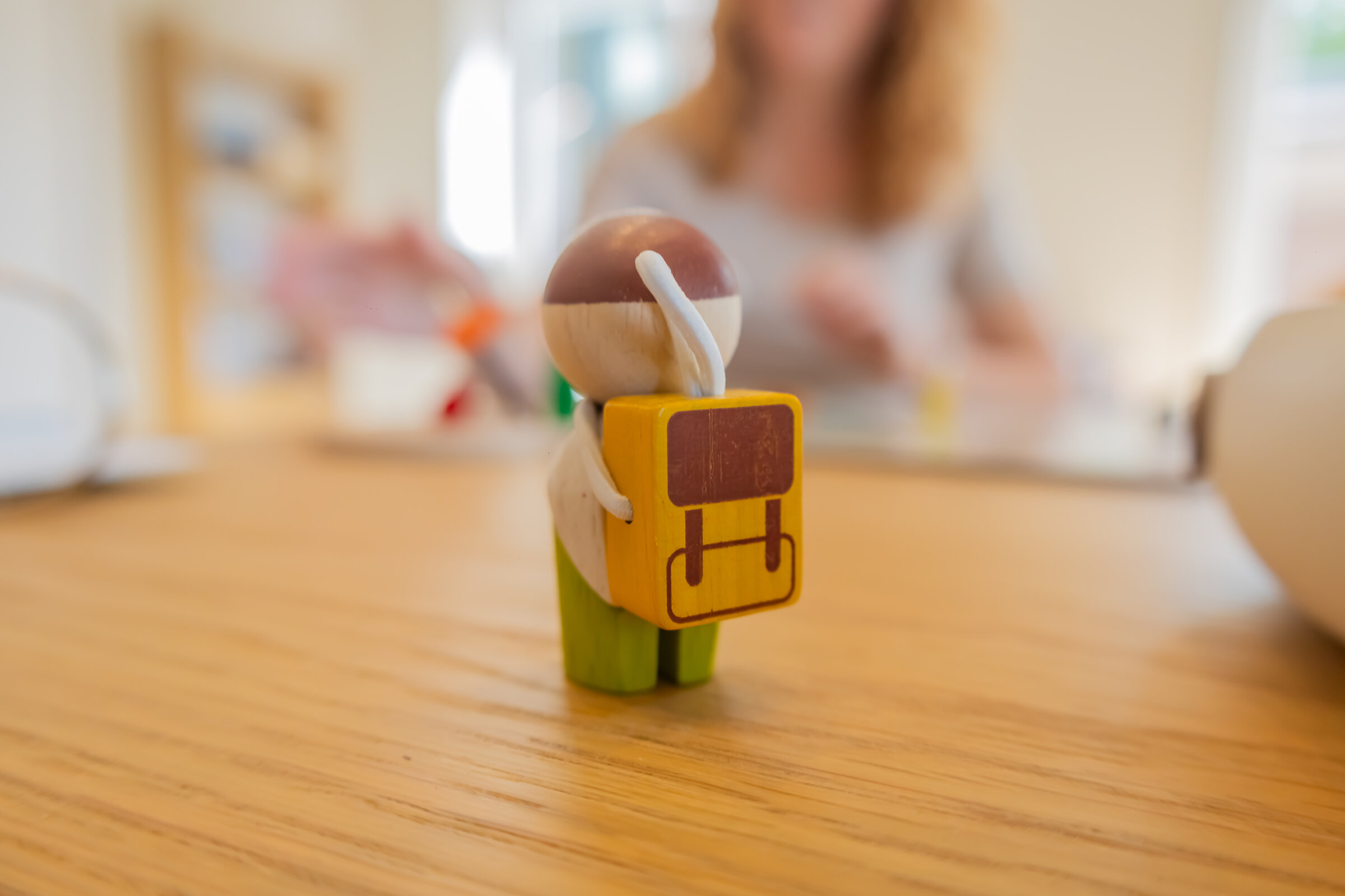 Houten poppetje met rugzakje op tafel — wat je meedraagt